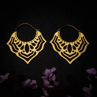 KIWA jewellery brand product image of a pair of brass material earrings called Asha, set on a dark granite background with dark pink coloured flower decoration on the lower end.