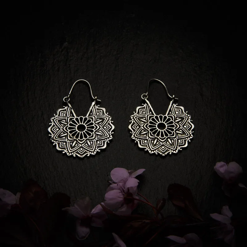 KIWA jewellery brand product image of a pair of silver plated earrings called Bali , set on a dark granite background with dark pink coloured flower decoration on the lower end.