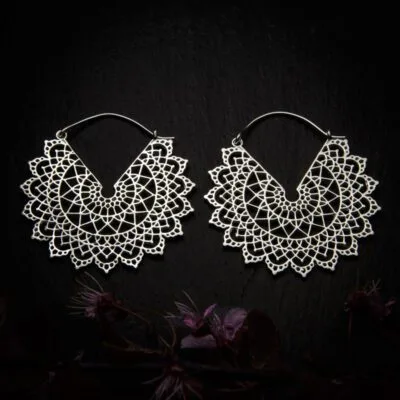 KIWA jewellery brand product image of a pair of silver plated earrings called Basilicum, set on a dark granite background with dark purple coloured flower decoration on the lower end.