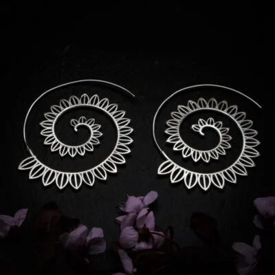 KIWA jewellery brand product image of a pair of silver plated earrings called Big spirals , set on a dark granite background with dark pink coloured flower decoration on the lower end.
