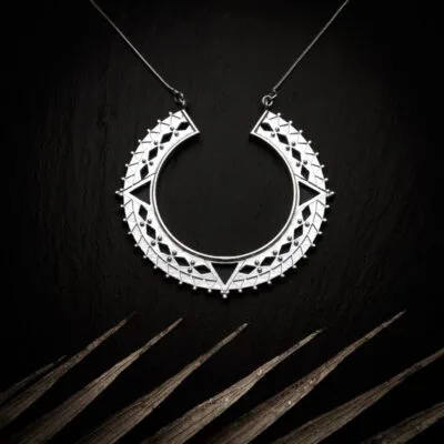 KIWA jewellery brand product image of a star model silver plated pendant necklace called Bozo. The necklace is set on a dark granite background with light colored leaf decoration on the lower end