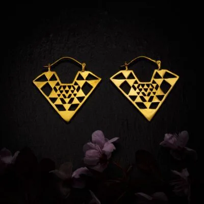 KIWA jewellery brand product image of a pair of brass material earrings called Diamond, set on a dark granite background with dark pink coloured flower decoration on the lower end.