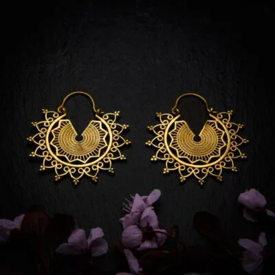 KIWA jewellery brand product image of a pair of brass material earrings called Emilia , set on a dark granite background with dark pink coloured flower decoration on the lower end.