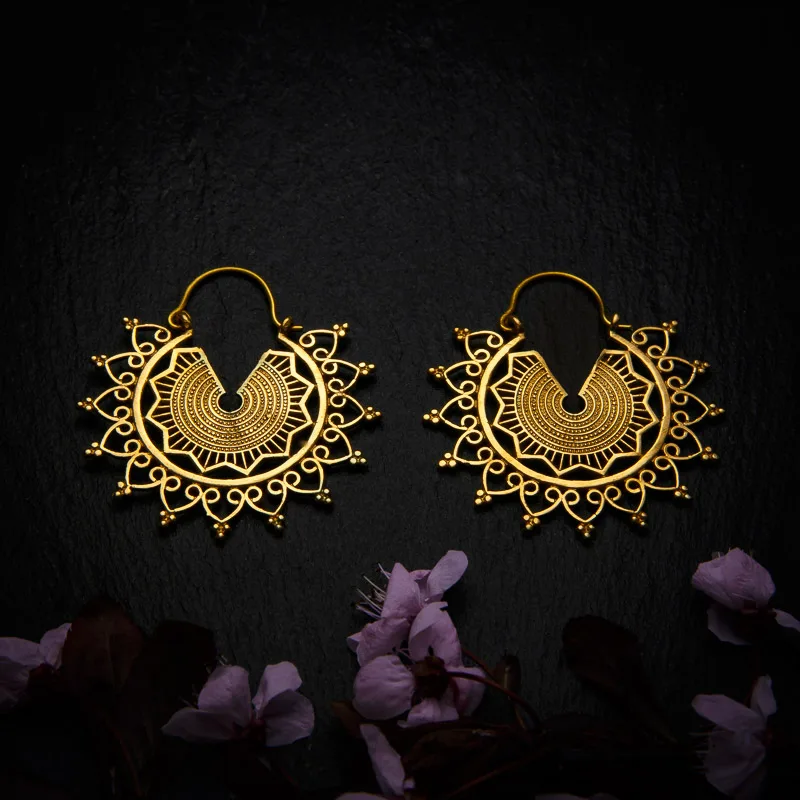 KIWA jewellery brand product image of a pair of brass material earrings called Emilia , set on a dark granite background with dark pink coloured flower decoration on the lower end.