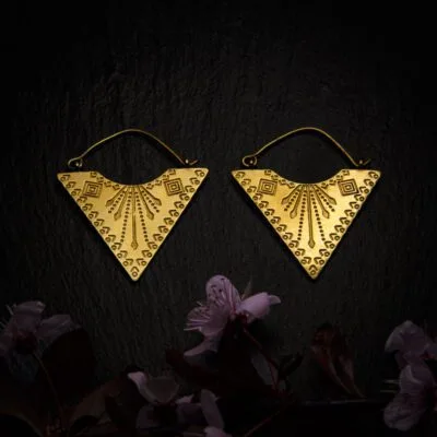 KIWA jewellery brand product image of a pair of brass material earrings called Etnica, set on a dark granite background with dark pink coloured flower decoration on the lower end.