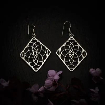 KIWA jewellery brand product image of a pair of silver plated earrings called Experience, set on a dark granite background with dark pink coloured flower decoration on the lower end.