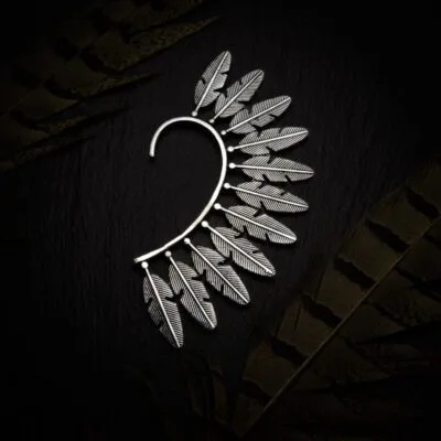 KIWA jewellery brand product image of a single silver plated earring called the Feather earcuff. The earcuff is set on a dark granite background with feather decoration