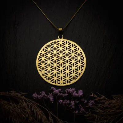 KIWA jewellery brand product image of a brass material pendant necklace called Flower of Life. The necklace is set on a dark granite background with hay and dark purple flower decoration on the lower end