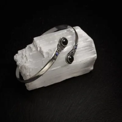 KIWA jewellery brand product image of a single silver plated armlet called the Four stone armlet. The armlet has a turqoise stone, but it comes in varieties. The armlet is set on a dark granite background on a selenite stone