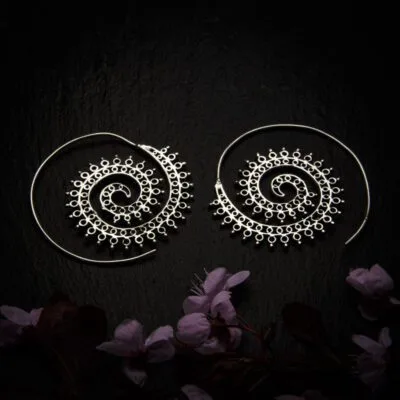 KIWA jewellery brand product image of a pair of silver plated earrings called the Funky Spirals, set on a dark granite background with dark pink coloured flower decoration on the lower end.