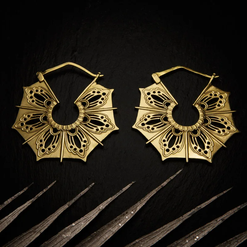 KIWA jewellery brand product image of a pair of brass material earrings called Gaia, set on a dark granite background with light coloured leaf decoration on the lower end.