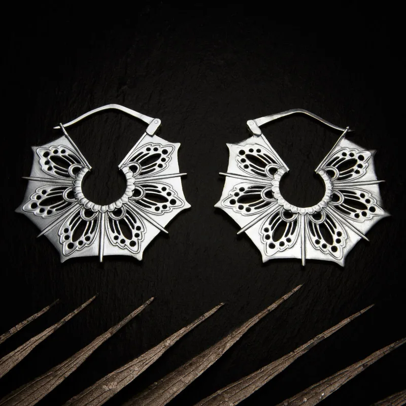 KIWA jewellery brand product image of a pair of silver plated earrings called Gaia, set on a dark granite background with light coloured leaf decoration on the lower end.