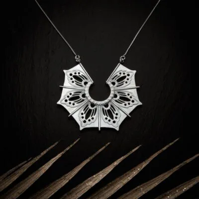 KIWA jewellery brand product image of a silver plated pendant necklace called Gaia. The necklace is set on a dark granite background with light colored leaf decoration on the lower end