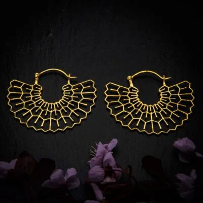 KIWA jewellery brand product image of a pair of brass material earrings called Happiness, set on a dark granite background with dark pink coloured flower decoration on the lower end.