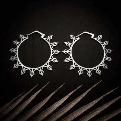 KIWA jewellery brand product image of a pair of silver plated earrings called Helia set on a dark granite background with light coloured leaf decoration on the lower end.