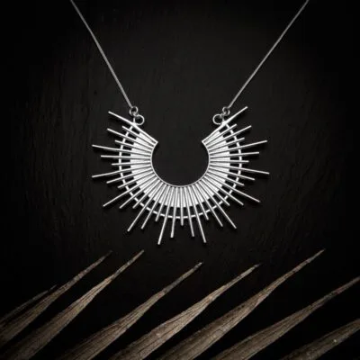 KIWA jewellery brand product image of a silver plated pendant necklace called Ida. The necklace is set on a dark granite background with light colored leaf decoration on the lower end