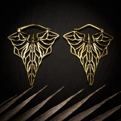 KIWA jewellery brand product image of a pair of brass material earrings called Kali, set on a dark granite background with light coloured leaf decoration on the lower end.