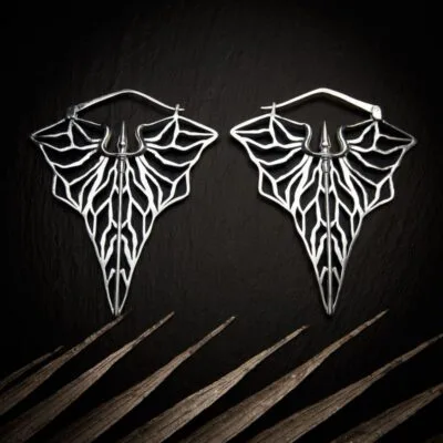 KIWA jewellery brand product image of a pair of silver plated earrings called Kali set on a dark granite background with light coloured leaf decoration on the lower end. KIWA kolekcija, srebrne mindjuse