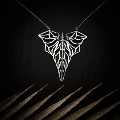 KIWA jewellery brand product image of a silver plated pendant necklace called Kali. The necklace is set on a dark granite background with light colored leaf decoration on the lower end