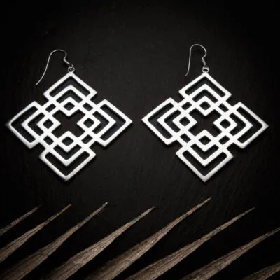 KIWA jewellery brand product image of a pair of silver plated earrings called Mokosha set on a dark granite background with light coloured leaf decoration on the lower end.