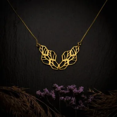 KIWA jewellery brand product image of a single brass material necklace called the Network, set on a dark granite background with hay and dark purpe flower decoration on the lower end