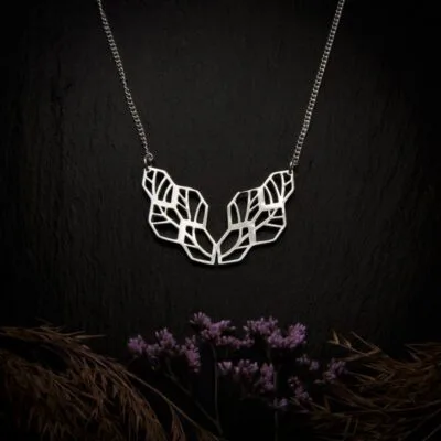 KIWA jewellery brand product image of a silver plated pendant necklace called the Network. The necklace is set on a dark granite background with hay and dark purple flower decoration on the lower end
