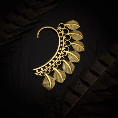 KIWA jewellery brand product image of a single brass material earring called the Serenity earcuff. The earcuff is set on a dark granite background with feather decoration
