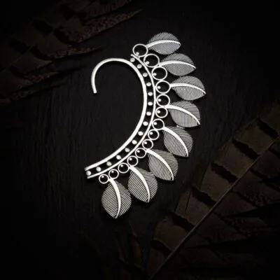 KIWA jewellery brand product image of a single silver plated earring called the Serenity earcuff. The earcuff is set on a dark granite background with feather decoration
