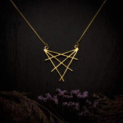 KIWA jewellery brand product image of a single brass material necklace called Shibuya, set on a dark granite background with hay and dark purpe flower decoration on the lower end