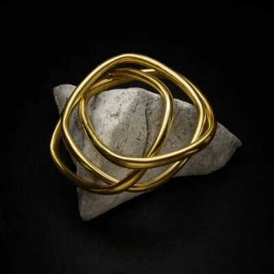KIWA jewellery brand product image of a single brass triple bracelet called Taboo choker set on a dark granite background on a white rock. KIWA narukvice, silver bracelet