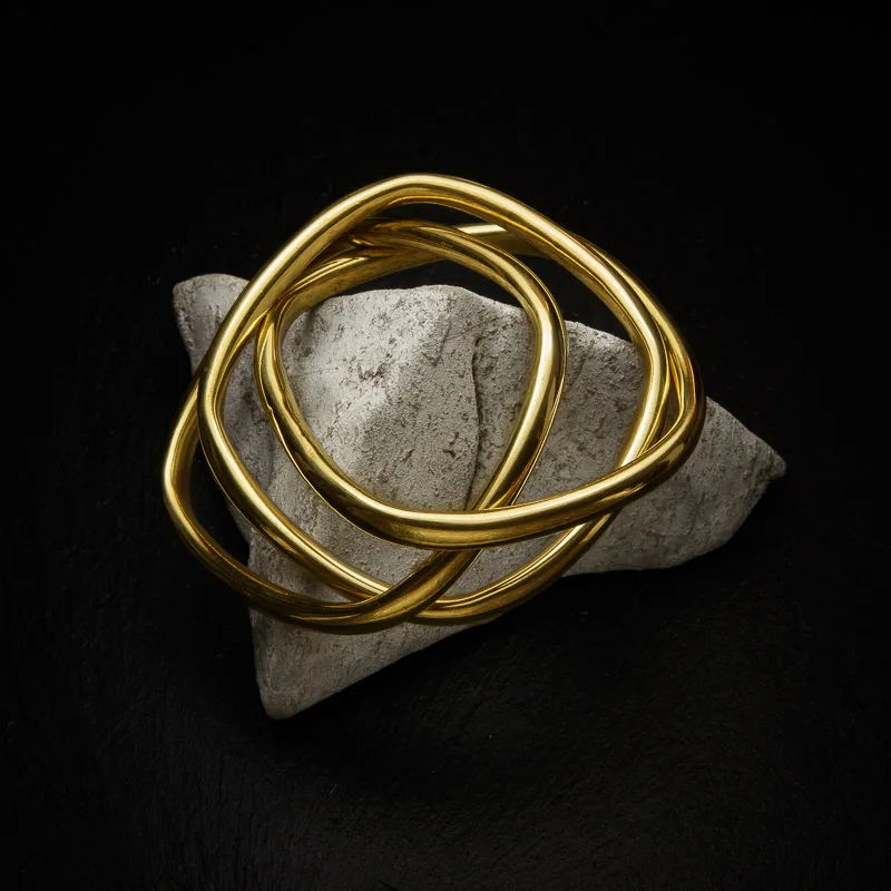 KIWA jewellery brand product image of a single brass triple bracelet called Taboo choker set on a dark granite background on a white rock.