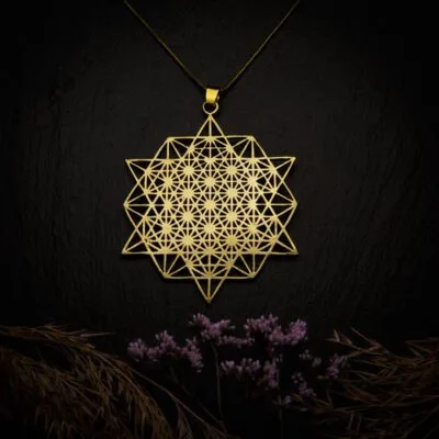 KIWA jewellery brand product image of a single brass material necklace called Tetrahedron, set on a dark granite background with hay and dark purpe flower decoration on the lower end