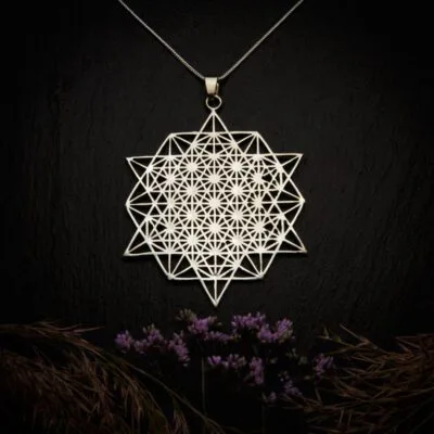 KIWA jewellery brand product image of a silver plated pendant necklace called Tetrahedron. The necklace is set on a dark granite background with hay and dark purple flower decoration on the lower end