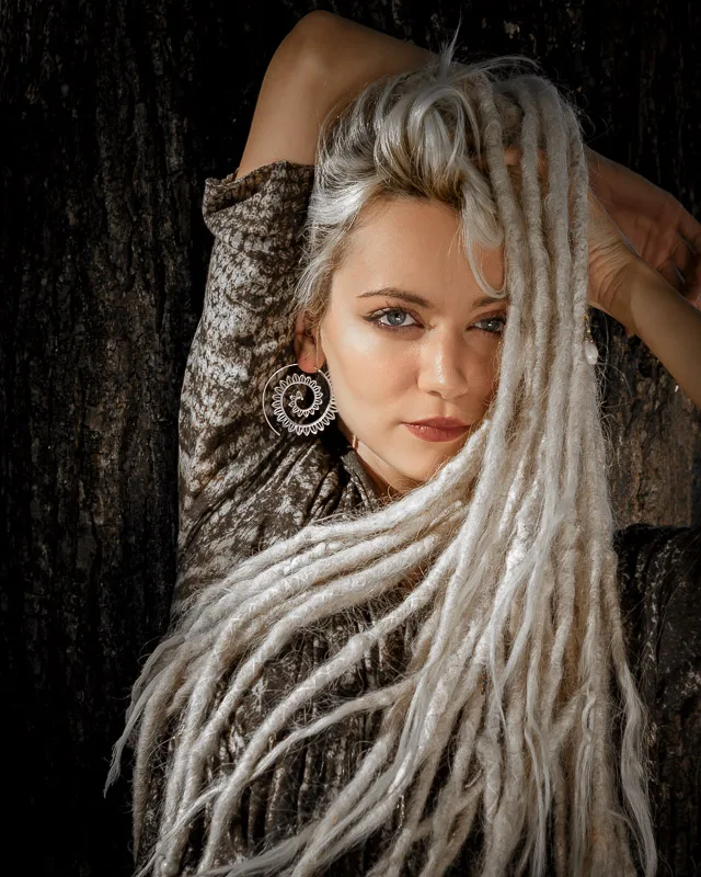 Photo of the beautiful Female model Yefimiya wearing Big Spirals Earrings Silver Plated from KIWA Jewellery against a tree trump dark background and with silver dreads spreading all across the animal print shirt