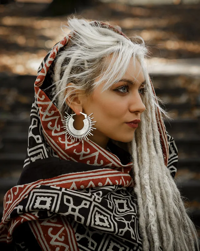 Photo of a Female model Yefimiya wearing Ida Silver plated Earrings from KIWA Jewellery hand crafted design. The model is wrapped up in a arabian looking scarf while her white dreads are falling out of the wrap.