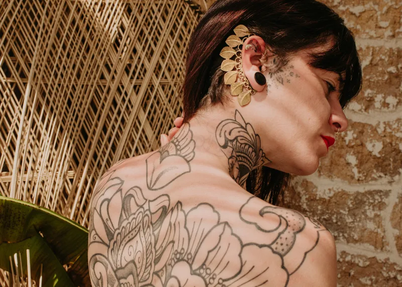 Photo of a Female model wearing Serenity Earcuff Brass from KIWA Jewellery while showing off her tatoos in a moroccan style setting